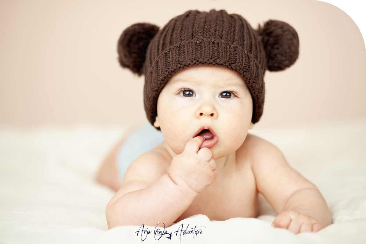 baby wearing a brown bear ears hat matching his brown eyes
