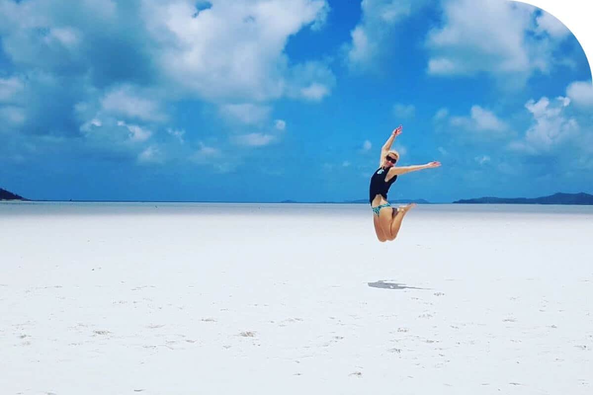 Anja On Adventure jumping on a silicate Whitehaven beach on whitsunday Island in Queensland, Australia